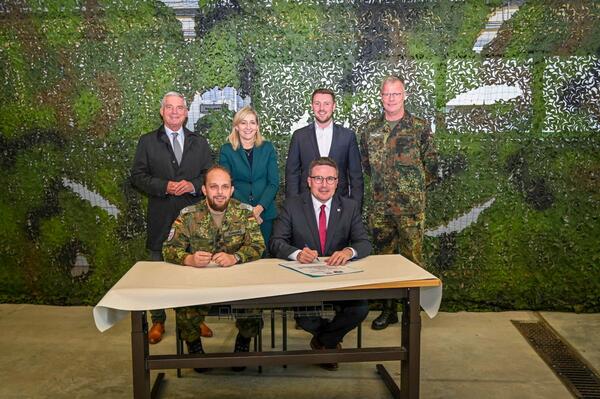Stellvertretender Regimentskommandeur Oberstleutnant Tobias Schwarz (vordere Reihe links) und Landrat Christoph Schauder (vordere Reihe rechts) unterzeichnen die neue Patenschaftsurkunde zwischen dem Main-Tauber-Kreis und dem Transporthubschrauberregiment 30 Tauberfranken. Die Urkunde wurde um den Beinamen erg�nzt. �ber die Verleihung des Beinamens freuten sich Innenminister Thomas Strobl (hintere Reihe von links), Nina Warken MdB, Kevin Leiser MdB und Oberst Dirk Meckelholt.