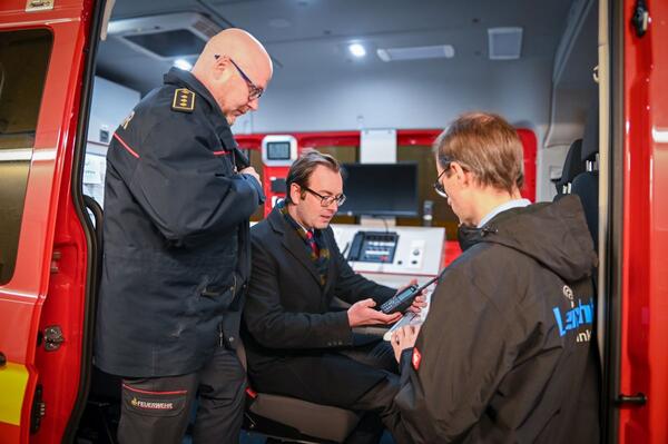 Bild vergr&ouml;&szlig;ern: Das Foto zeigt Ersten Landesbeamten Florian Busch, der sich auf der Feuerwache in Bad Mergentheim im Einsatzleitwagen von der neuen Technik überzeugte. Kreisbrandmeister Andreas Geyer (l.) und Christoph Graf-Hadry von der Firma Leicht Funktechnik (r.) erklärten die technische Ausstattung.
