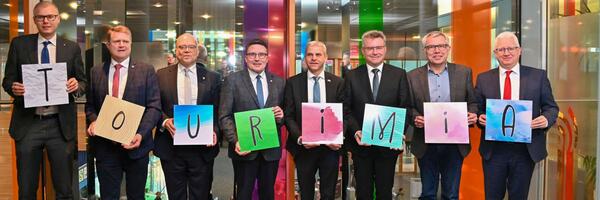 Oberb�rgermeister Daniel Bullinger (Stellvertretender Vorsitzender Hohenlohe + Schw�bisch Hall Tourismus e.V.), Oberb�rgermeister Martin Wolff (Vorsitzender Kraichgau-Stromberg Tourismus e.V.), Landrat Norbert Heuser (Vorsitzender Touristikgemeinschaft HeilbronnerLand e.V.), Landrat Christoph Schauder (Vorsitzender Tourismusverband "Liebliches Taubertal" e.V.), Staatssekret�r Dr. Patrick Rapp MdL (Ministerium f�r Wirtschaft, Arbeit und Tourismus Baden-W�rttemberg), Landrat Dr. Achim Br�tel (Vorsitzender Touristikgemeinschaft Odenwald e.V.), Landrat Stefan Dallinger (Rhein-Neckar-Kreis) und Erster Landesbeamter Gotthard Wirth (Stellvertretender Vorsitzender Touristikgemeinschaft Hohenlohe e.V.) pr�sentieren den Namen der neuen touristischen Dach-DMO: Tourimia.