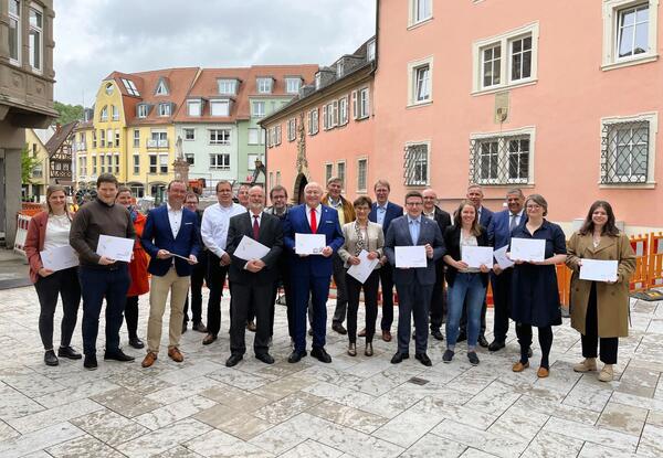 OB Udo Glatthaar (Mitte) �berreichte vor der Kulisse des "Starterprojektes" G�nsmarkt den Rahmenplan f�r die Landesgartenschau an Staatssekret�rin Sabine Kurtz MdL (rechts neben ihm) und Ralph K�nig (links von ihm) im Beisein von Landrat Christoph Schauder (7. von rechts) und weiteren G�sten sowie den Gesichtern der Landesgartenschau Bad Mergentheim.