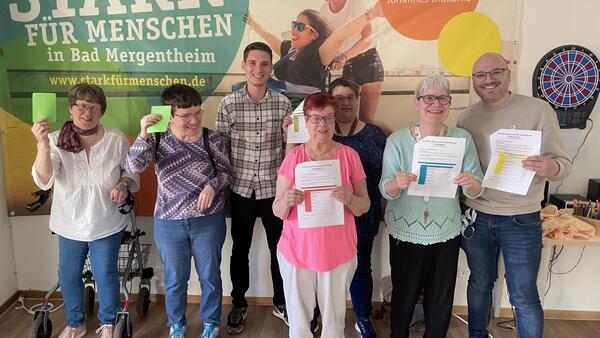 Bild vergr&ouml;&szlig;ern: Das Foto zeigt strahlende Gesichter beim Workshop in der Johannes-Diakonie in Bad Mergentheim: Erstmalig dürfen Menschen mit geistiger Behinderung oder kognitiver Beeinträchtigung in diesem Jahr an den anstehenden Europa- und Kommunalwahlen teilnehmen.