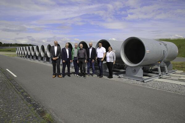 Systemair Seitenwind-Simulationsanlage mit Projektbeteiligten: Whrend des Besuchs des Systemair-Teams bei der Robert Bosch GmbH im Bosch-Prfzentrum Boxberg tauschten sich die Projektbeteiligten (von links) aus: Projektverantwortlicher Arthur Palmer und der ehemalige Geschftsfhrer Stefan Fischer (beide Fa. Systemair) sowie das Bosch-Team mit Facilitymanager Mathias Angermann, Kaufmnnischer Betriebsleiter Andreas Wachter, Standortleiter Joachim Schorr, Projektleiter Markus Rheinhold und die Technische Betriebsleiterin Sarah Doyle. Die Seitenwind-Simulationsanlage besteht aus 15 Strahlventilatoren AJ 1250 55 kW. Getestet wurde im Anschluss exemplarisch anhand der Vorbeifahrt mit einem Kleintransporter.