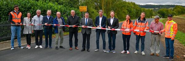 F�nf Kreisstra�en-Abschnitte haben in den Ferien eine neue Fahrbahndecke erhalten: In Gro�rinderfeld-Ilmspan hat Landrat Christoph Schauder (Bildmitte) gemeinsam mit den Fraktionsvorsitzenden des Kreistags sowie Vertretern der Gemeinde Gro�rinderfeld, des Stra�enbauamtes und der zust�ndigen Baufirma stellvertretend f�r alle Ma�nahmen den sanierten Streckenabschnitt der Kreisstra�e K 2882 er�ffnet.