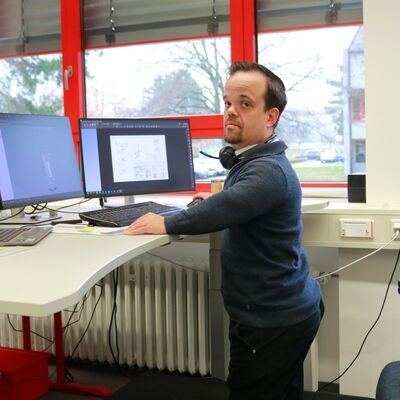 Max Hachtel ist seit 2022 bei W�rth Industrie Service t�tig. Mit einem h�henverstellbaren Schreibtisch, einem ma�gefertigten B�rostuhl und einem Podest, das ihm die freie Sicht auf seine Umgebung erm�glicht, wurde ein Umfeld gestaltet, das seinen Bed�rfnissen bestm�glich gerecht wird.