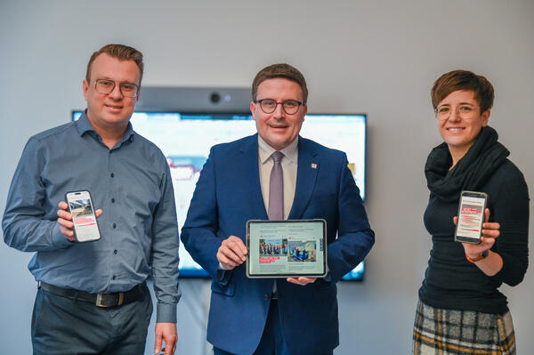 Landrat Christoph Schauder (Mitte), sein B�roleiter Markus Moll und Julia Pfaff, Mitarbeiterin f�r Websiteentwicklung, freuen sich �ber die Integration der Social Media Wall �Stage� in die Homepage des Main-Tauber-Kreises. 