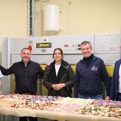 Handwerk trifft Kulinarik in der Gewerblichen Schule Tauberbischofsheim: Rocco Carella (2.v.l.) und sein Team von Carellas Ristorante versorgten die Teilnehmer mit einer einzigartigen Pizza. Ebenso einzigartig: Abteilungsleiter J�rg Schwab (v.r.), Schulleiter Hermann Ruppert und die Fachlehrer backten die 180 Zentimeter lange Pizza in der hauseigenen Furnierpresse der Schule.