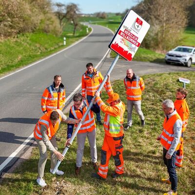 Selbst mit Hand angelegt: Landrat Christoph Schauder (3.v.l.) und Ahorns B�rgermeister Benjamin Czernin (l.) haben gemeinsam mit Mitarbeitern des Stra�enbauamtes an der Landkreisgrenze bei der Kreisstra�e K 2885 zwischen Schillingstadt (Gemeinde Ahorn) und Oberwittstadt (Stadt Ravenstein) die neu gestalteten Kreisgrenzschilder aufgestellt.