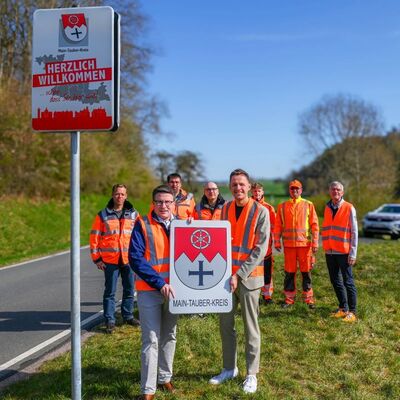 Das neue Schild h�ngt, das alte wird zum Geschenk: Landrat Christoph Schauder (vorne links) �bergab das bisher an der Landkreisgrenze im Einsatz befindliche Schild an B�rgermeister Benjamin Czernin. 