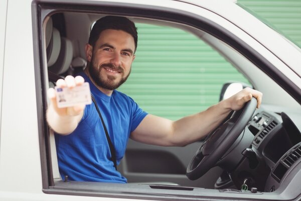 Ein Mann in einem Lieferwagen zeigt seinen F�hrerschein im Scheckkartenformat: Wer einen unbefristeten Kartenf�hrerschein besitzt, der in den Jahren 1999 bis 2001 ausgegeben wurde, muss diesen bis zum 19. Januar 2026 in einen befristeten EU-F�hrerschein umtauschen. Antr�ge sollten z�gig gestellt werden.