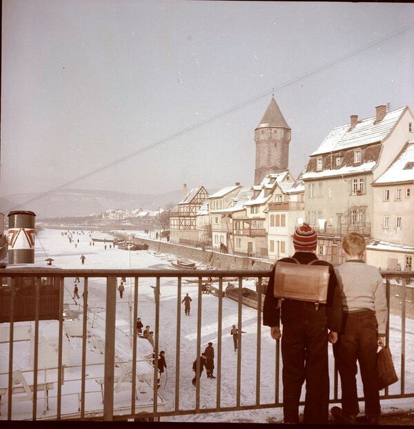 Das Foto zeigt ein altes Foto, auf dem Kinder auf der Tauber Eislaufen. 