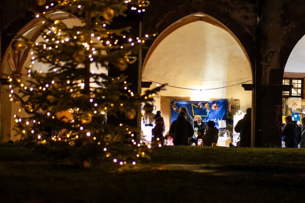 Das Foto zeigt den Bronnbacher Weihnachtsmarkt im Kreuzgang bei Nacht.