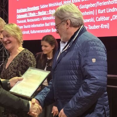 G�stef�hrer Kurt Lindner erh�lt aus den H�nden von Staatssekret�r Dr. Patrick Rapp die Ernennungsurkunde zum "Tourismushelden 2026".