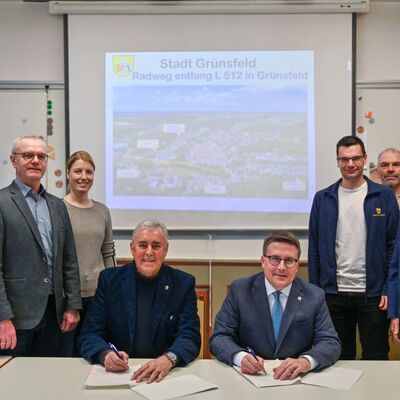 Landrat Christoph Schauder (vierter von rechts) und B�rgermeister Joachim Markert (vierter von links) unterzeichnen die Vereinbarung f�r den Radweg entlang der L 512 in Gr�nsfeld. Dar�ber freuen sich (v. r.) Technik-Dezernent Werner R�ger, Sebastian Bokmeier (Amt f�r Stra�en- und Radwegebau), Gabriel Weber, Christina Wenz (beide Stadt Gr�nsfeld), Markus Metz (Leiter des Amtes f�r Stra�en- und Radwegebau) sowie Christoph Kraft (Stadt Gr�nsfeld).