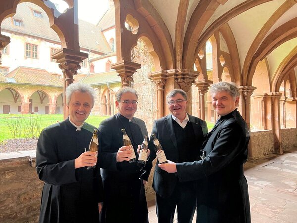 Das Foto zeigt vier M&ouml;nche im Kreuzgang des Klosters Bronnbach, die eine Flasche Bier in der Hand halten. 