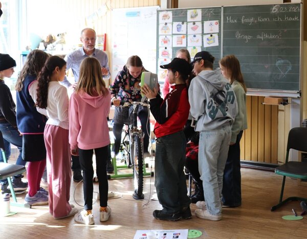Bild vergr&ouml;&szlig;ern: Das Foto zeigt die Schülerinnen und Schüler bei der Erzeugung von Strom für einen Ventilator mit dem Energie-Fahrrad.