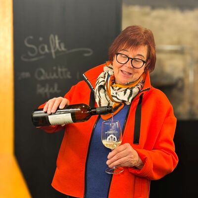 Bild vergr&ouml;&szlig;ern: Das Foto zeigt eine Frau, die Wein in ein Weinglas eingießt.