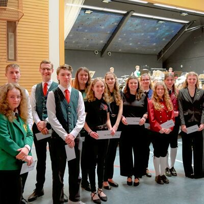 Landrat Christoph Schauder (rechts) ehrte in Assamstadt 13 Musikerinnen und Musiker des KJBO f�r die f�nfte Teilnahme am Kreisjugendblasorchester: Sie erhielten daf�r eine Ehrennadel sowie einen Gutschein des Musikhauses Martens in Schrozberg.