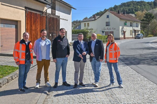 Die K 2881 wurde wetterfest gemacht (von links): Michael Suppinger (Sachgebietsleiter Planung und Bau vom Amt f�r Stra�en- und Radwegebau), Gesch�ftsf�hrer Sebastian Boller und Bauleiter Raphael Stang (Boller-Bau GmbH), Landrat Christoph Schauder, B�rgermeister Thomas Schreglmann und Projektleiterin Hanna Kuznetsova (Amt f�r Stra�en- und Radwegebau) besichtigen gemeinsam die instandgesetzte Entw�sserungsrinne in Eiersheim entlang der K 2881.