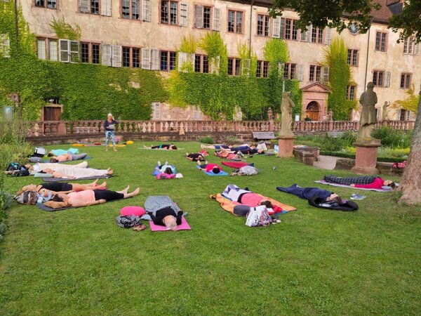 Das Foto zeigt die Teilnehmer eines Yogakurses im Abteigarten Kloster Bronnbach. 