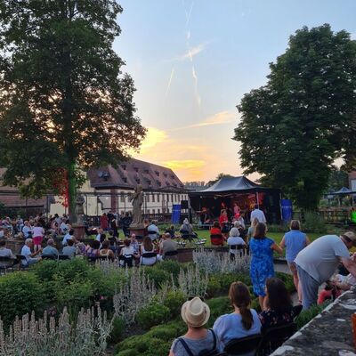 Das Lichterfest 2026 im Kloster Bronnbach: Im Abteigarten sorgte die Band �Groove Buzzters� f�r die passende Livemusik, bei k�hlen Cocktails, Softdrinks oder Wein lie� es sich dort trotz der hei�en Temperaturen gut aushalten. 