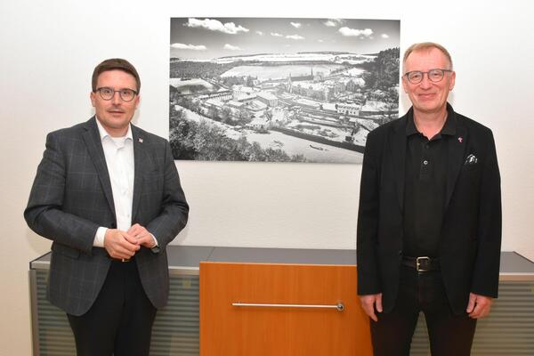 Landrat Christoph Schauder (links) und Pr�lat Ralf Albrecht vor einer Luftbildaufnahme der kreiseigenen Liegenschaft Kloster Bronnbach: Bei einem Antrittsgespr�ch tauschten sich beide unter anderem zum Thema Digitalisierung aus.