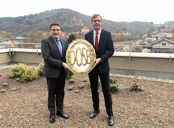 Landrat Christoph Schauder (links) und Vorstandsvorsitzender Peter Vogel mit dem Logo des Deutschen Olympischen Sportbunds. Schauder und Vogel rufen zur Teilnahme am Sportabzeichen-Wettbewerb der Sparkasse Tauberfranken auf.