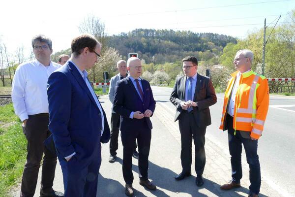 Bild vergr&ouml;&szlig;ern: Das Bild zeigt Stadtbaumeister Tobias Blessing, Bürgermeister Dr. Lukas Braun, Bürgermeister-Stellvertreter Hubert Segeritz, Parlamentarischen Staatssekretär Michael Theurer und Kreis-Straßenbauamtsleiter Michael Metz vor dem Doppelbahnübergang in Königshofen.
