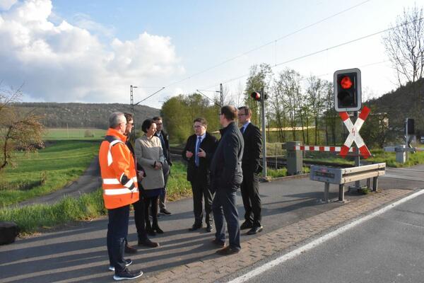 Bild vergr&ouml;&szlig;ern: Das Foto zeigt die Delegation des Regierungspräsidiums, die den Doppelbahnübergang in Königshofen zusammen mit Landrat Christoph Schauder, Erstem Landesbeamten Florian Busch, Straßenbauamtsleiter Markus Metz und Bürgermeister Dr. Lukas Braun besichtigt.