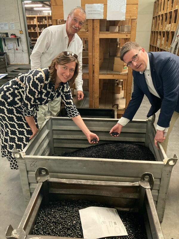 Bild vergr&ouml;&szlig;ern: Das Foto zeigt Bürgermeisterin Heidrun Beck, Gesellschafter Thomas Schnizler und Landrat Christoph Schauder an einer Schütte mit Schrauben.