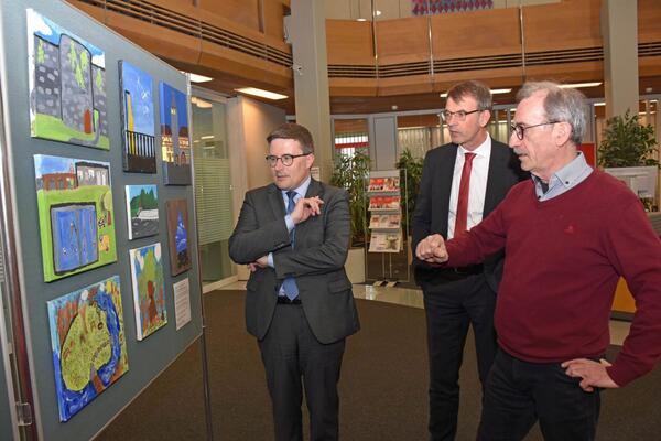 Eine Tafel im Rahmen der Ausstellung in der Sparkasse bndelt die besonders farbstarken Werke, die auf Leinwand eingereicht wurden: Landrat Christoph Schauder, Sparkassenchef Peter Vogel und Knstler Gunter Schmidt besichtigten die Ausstellung zum Jubilum "50 Jahre Main-Tauber-Kreis".