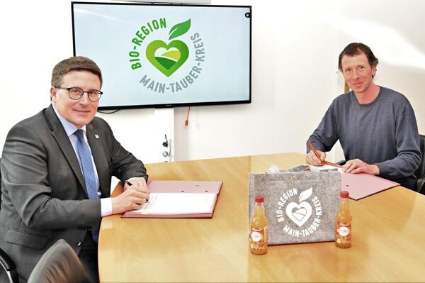 Landrat Christoph Schauder (links) und Vorstandsmitglied Tobias Hornung unterzeichnen den Bewirtschaftungsvertrag und die Beitrittserklrung des Landkreise zum Verein Tauberlnder Streuobstwiesen e.V.