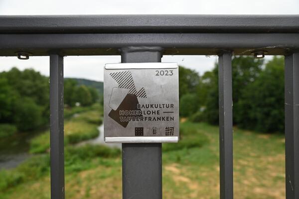 Bild vergr&ouml;&szlig;ern: Das Foto zeigt die Plakette der Baukulturinitiative Hohenlohe-Tauberfranken an der Tauberbrücke in Markelsheim: Die Brücke wurde im Frühjahr in der Kategorie Infrastrukturmaßnahmen ausgezeichnet.