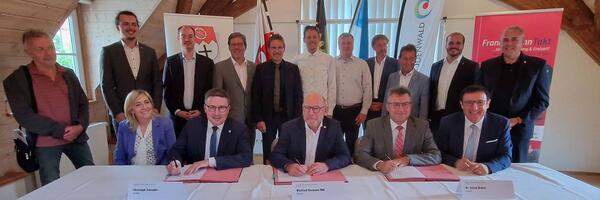 Den Vertrag zur Verstetigung des Regionalbahn-Stundentakts unterzeichneten (sitzend, 2. bis 4. von links) Landrat Christoph Schauder (Main-Tauber-Kreis), Verkehrsminister Winfried Hermann und Landrat Dr. Achim Br�tel (Neckar-Odenwald-Kreis), flankiert von der Bundestagsabgeordneten Nina Warken und Landtagsvizepr�sident Prof. Dr. Wolfgang Reinhart. Mit ihnen freuten sich weitere Landtagsabgeordnete, die B�rgermeister der Kommunen an der Bahnstrecke sowie Vertreter der B�rgerinitiative "Frankenbahn f�r Alle".