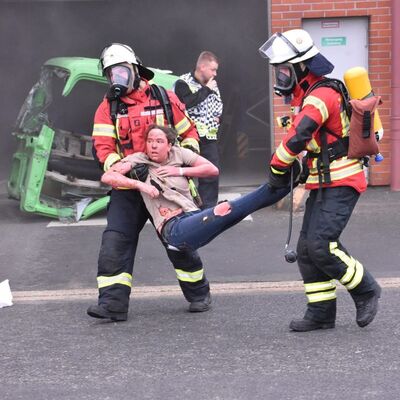 Bild vergr&ouml;&szlig;ern: Das Bild zeigt zwei Einsatzkräfte dabei, wie sie eine verletzte Person von einer Gefahrenlage wegtragen.