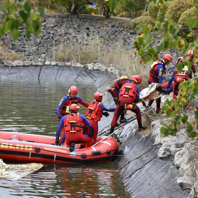 Bild vergr&ouml;&szlig;ern: Das Bild zeigt die Wasserrettung, während sie eine Person aus einem Löschteich in Sicherheit bringen.